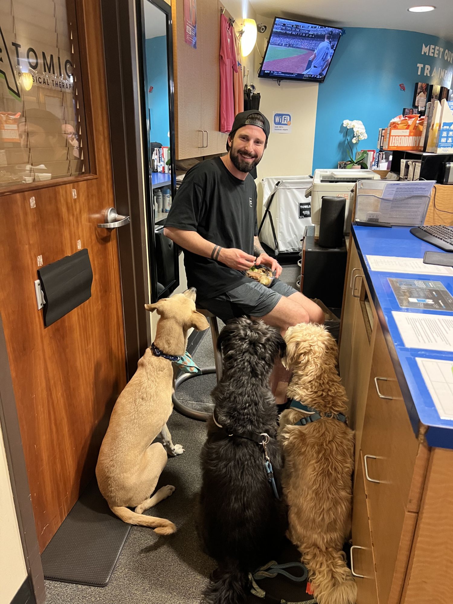 Someone at the front desk of ONE Boulder Fitness with three dogs waiting for a treat