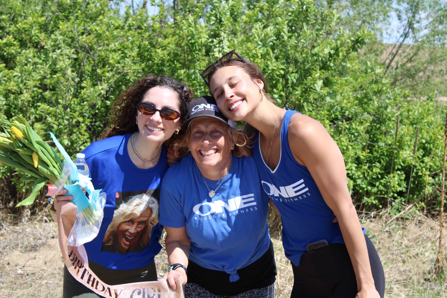 Three members in ONE shirts hugging outdoors after a run