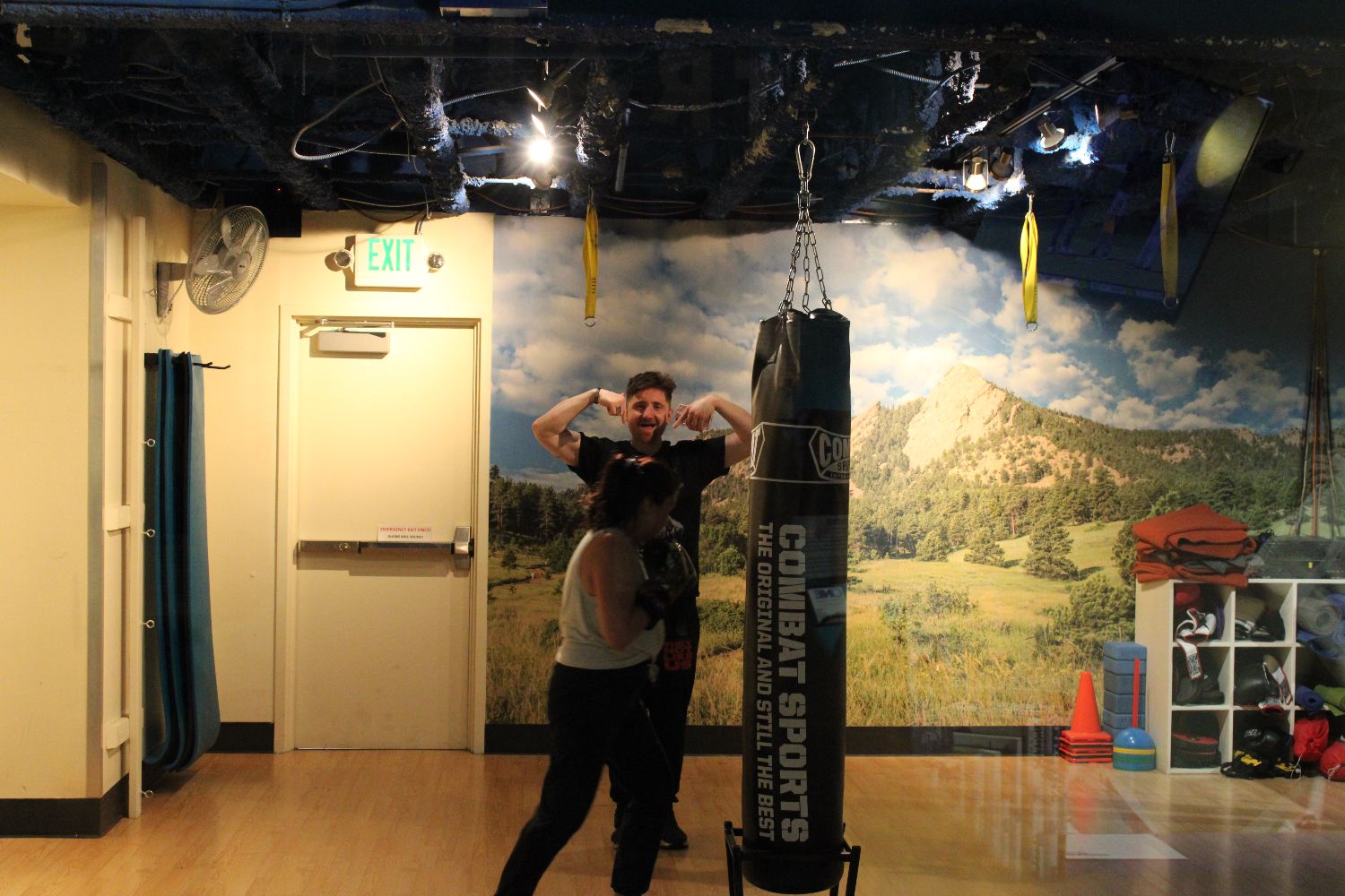 A member working the heavy bag in the studio, coached beside her